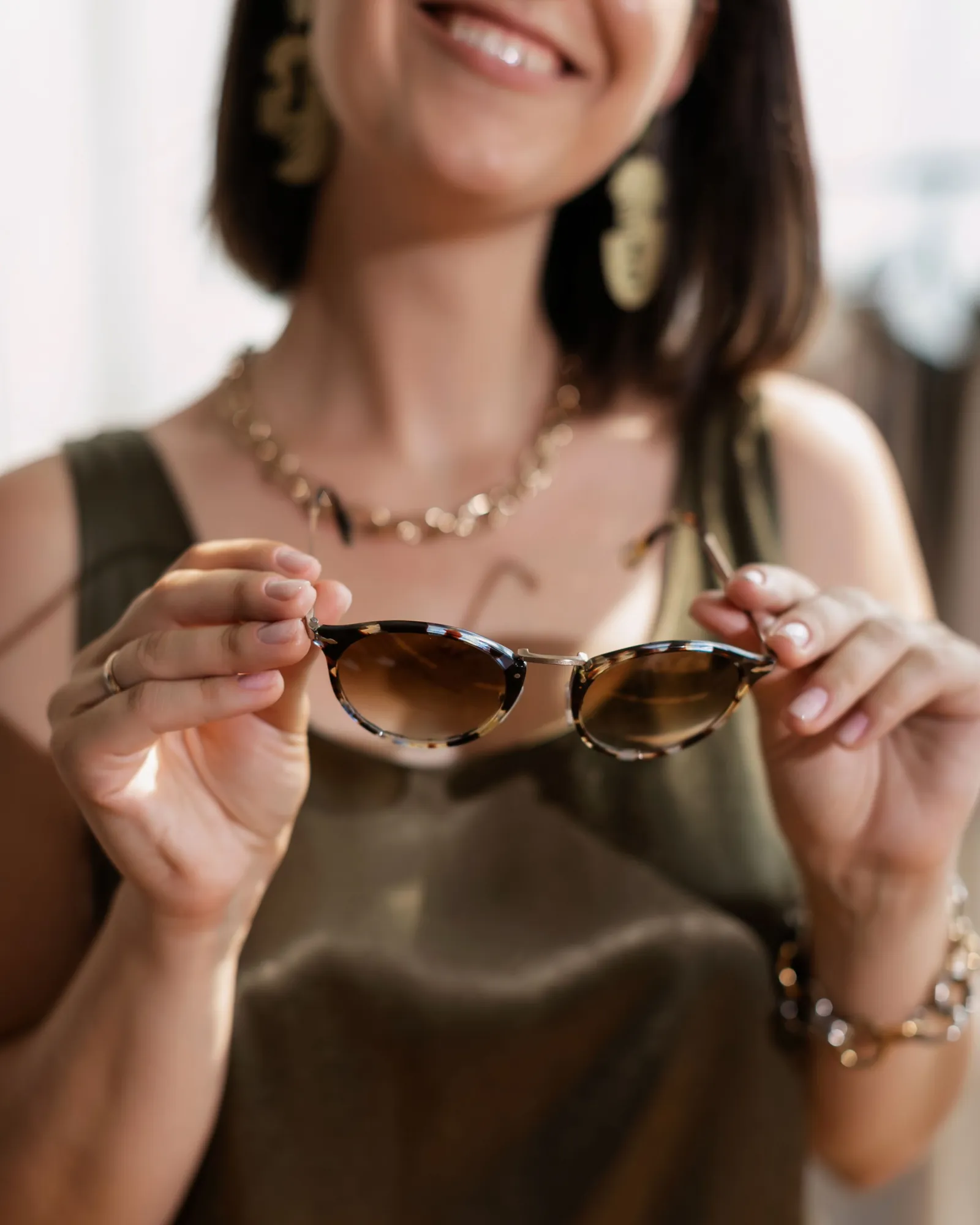 Mujer sosteniendo con ambas manos unas gafas de sol de carey con lentes marrones degradadas